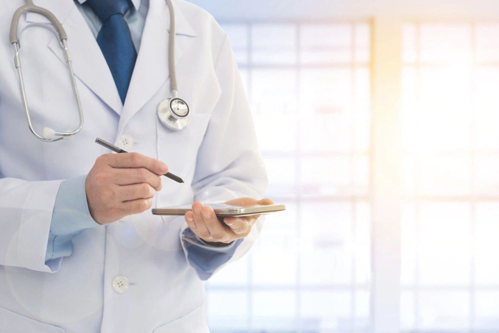 A doctor holding a pen and phone in his hand.